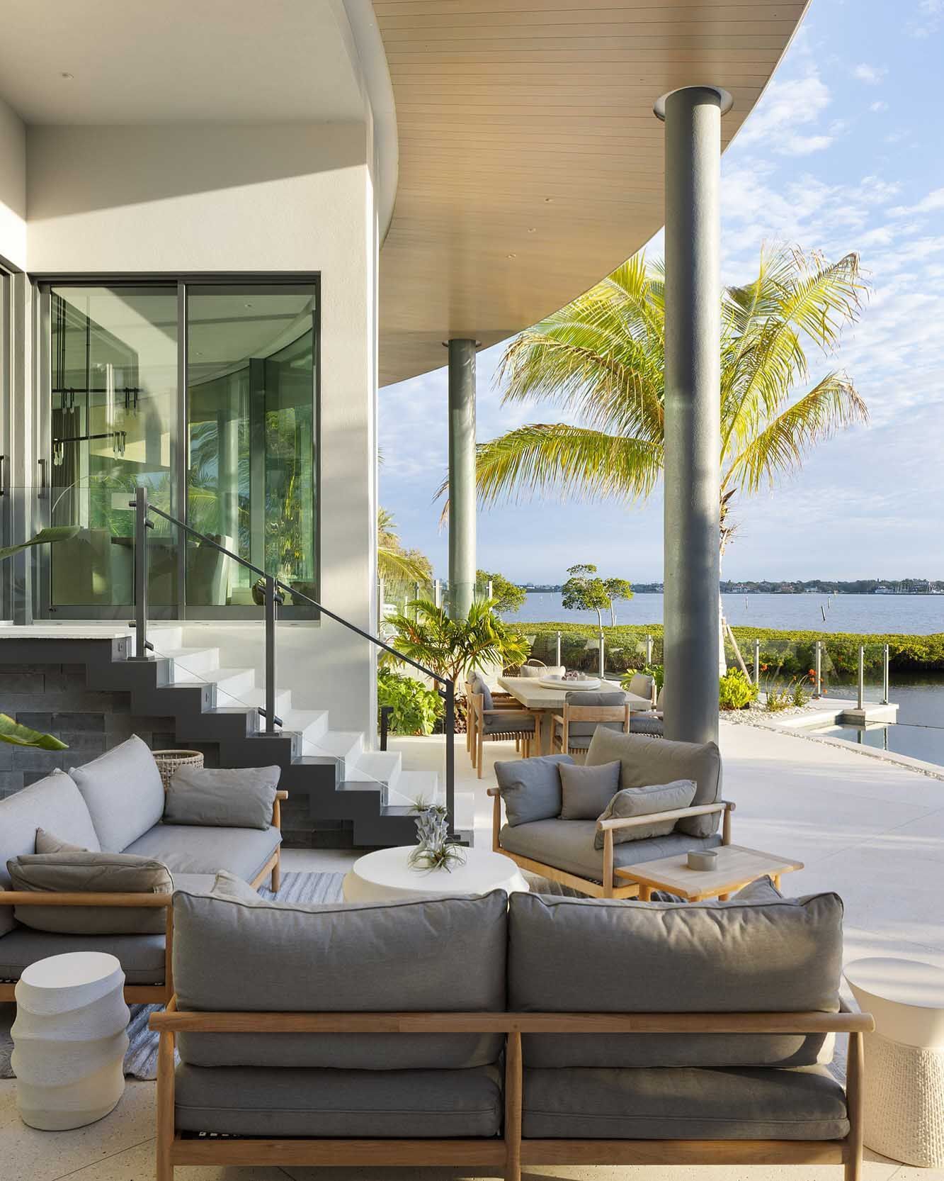 Outdoor seating area with gray furniture, overlooking water and greenery.