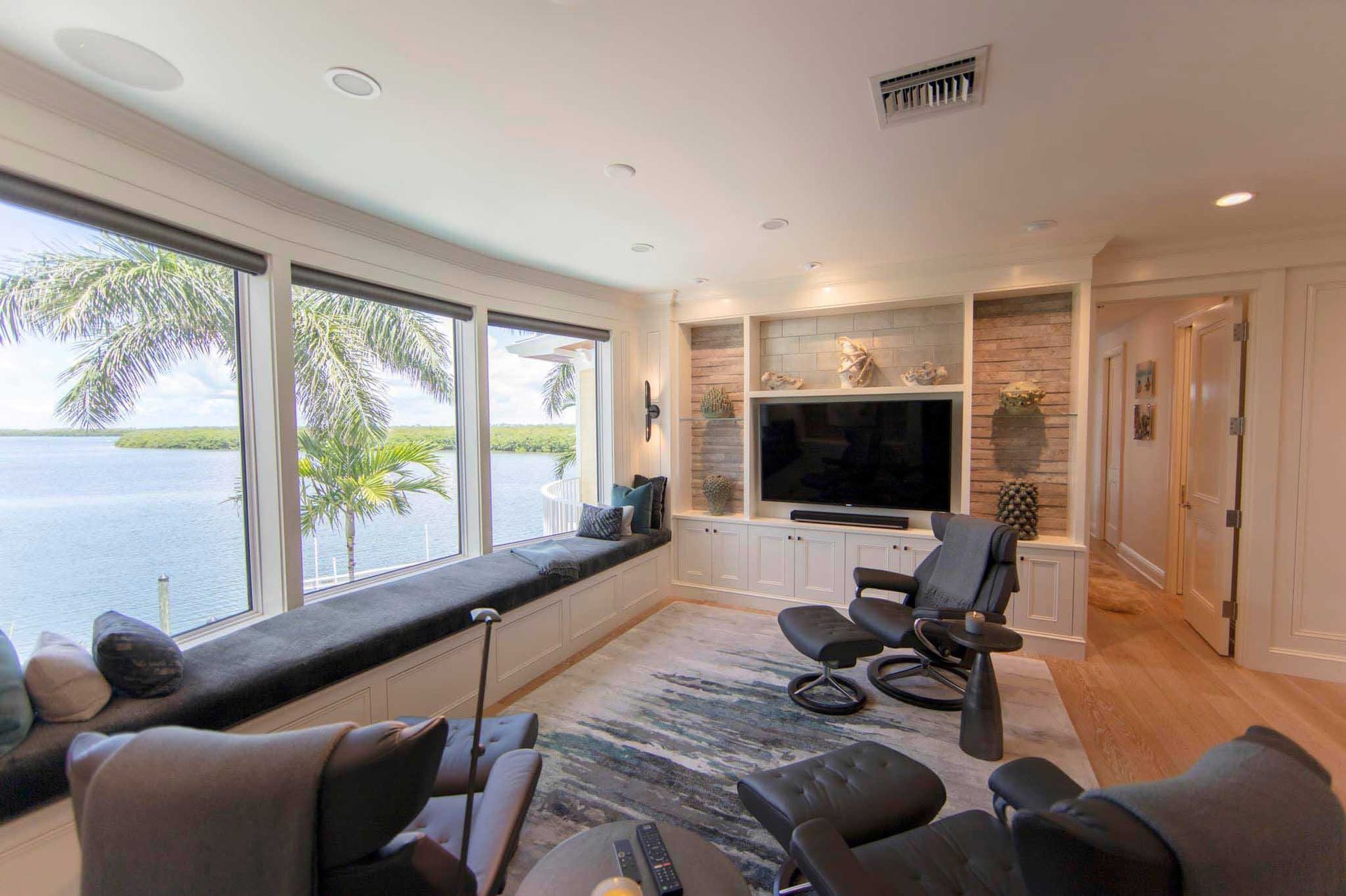 Living room with bay window, water view, built-in media center, and black leather recliners.