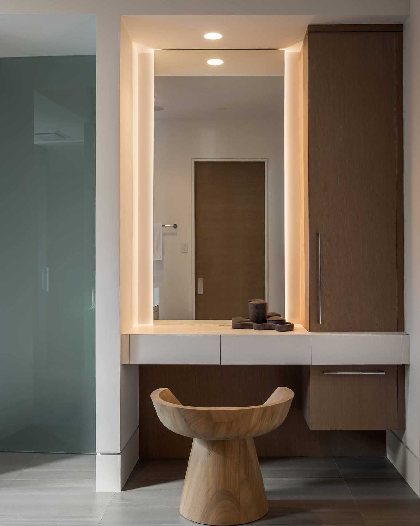 Vanity with large mirror, built-in lights, drawers, cabinet, and wooden stool.
