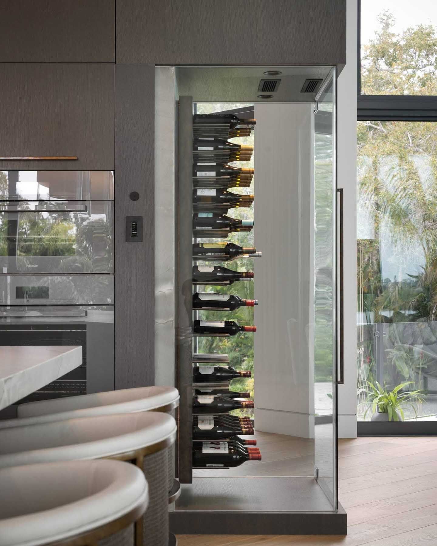 Modern kitchen with a built-in wine rack filled with bottles next to a large window.