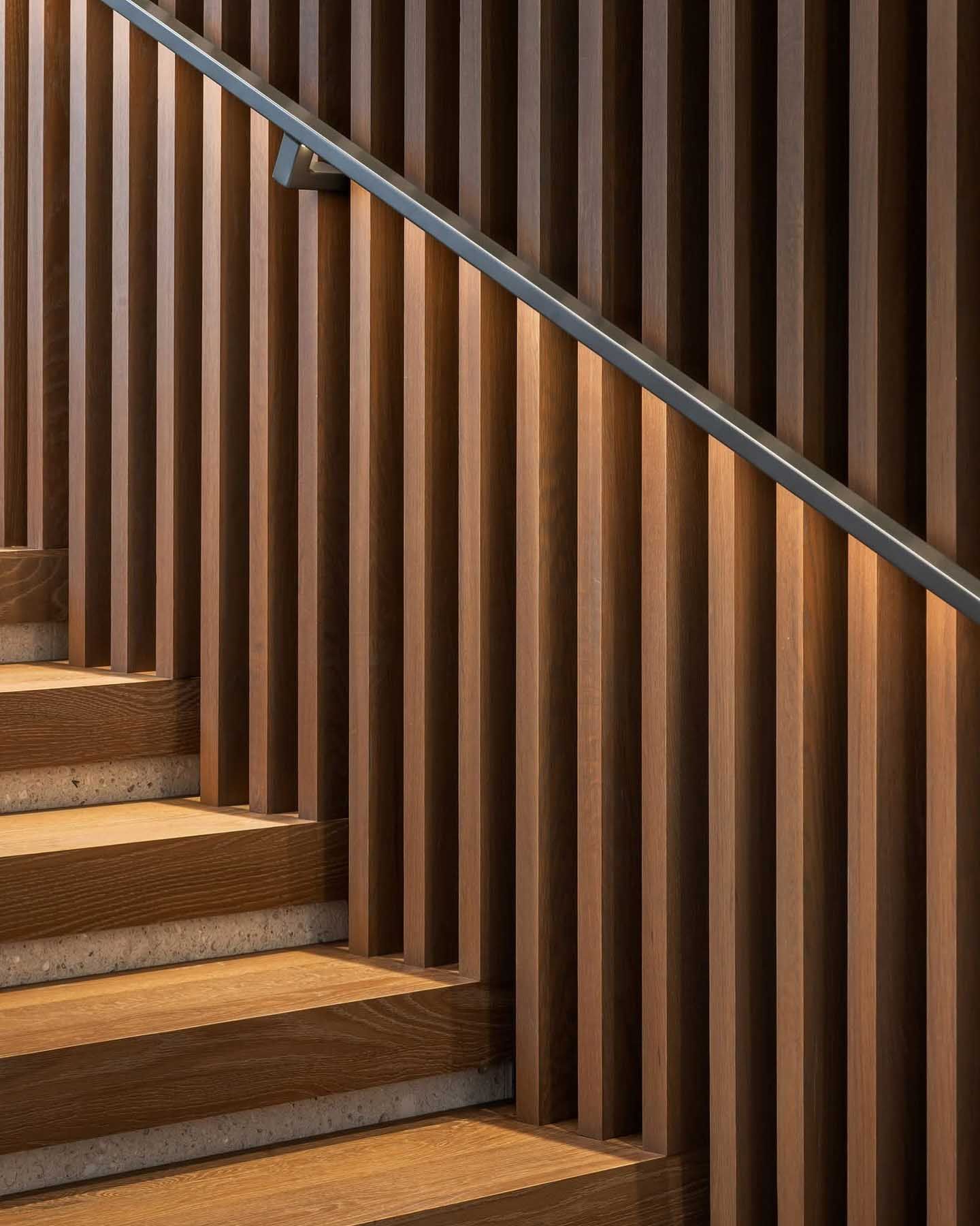 Wooden staircase with vertical wood paneling and a metal handrail.