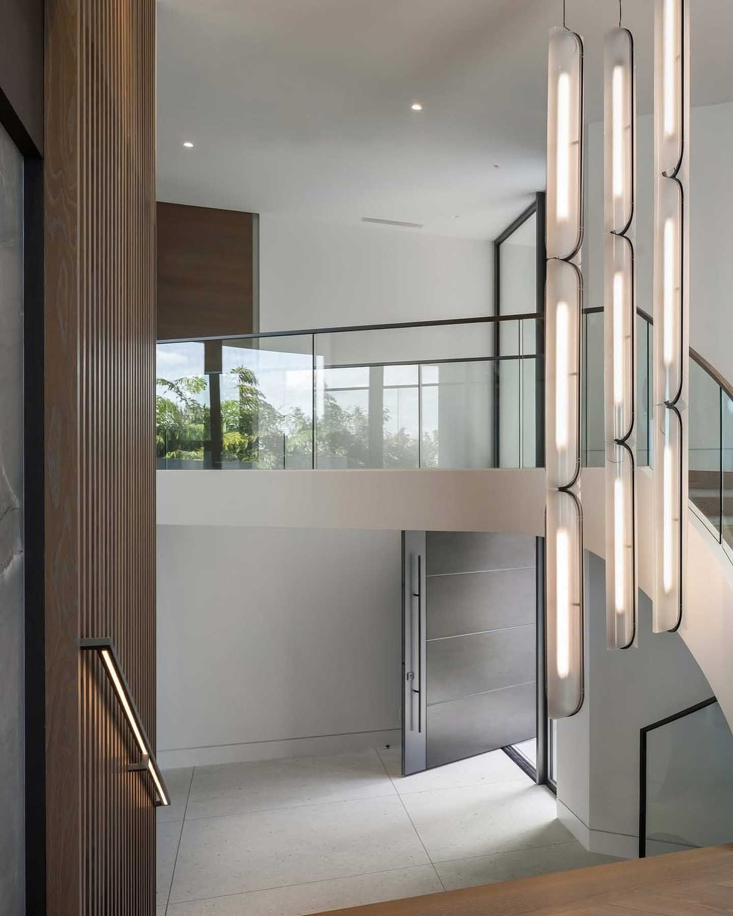 Modern home entryway with a hanging light fixture and a staircase.