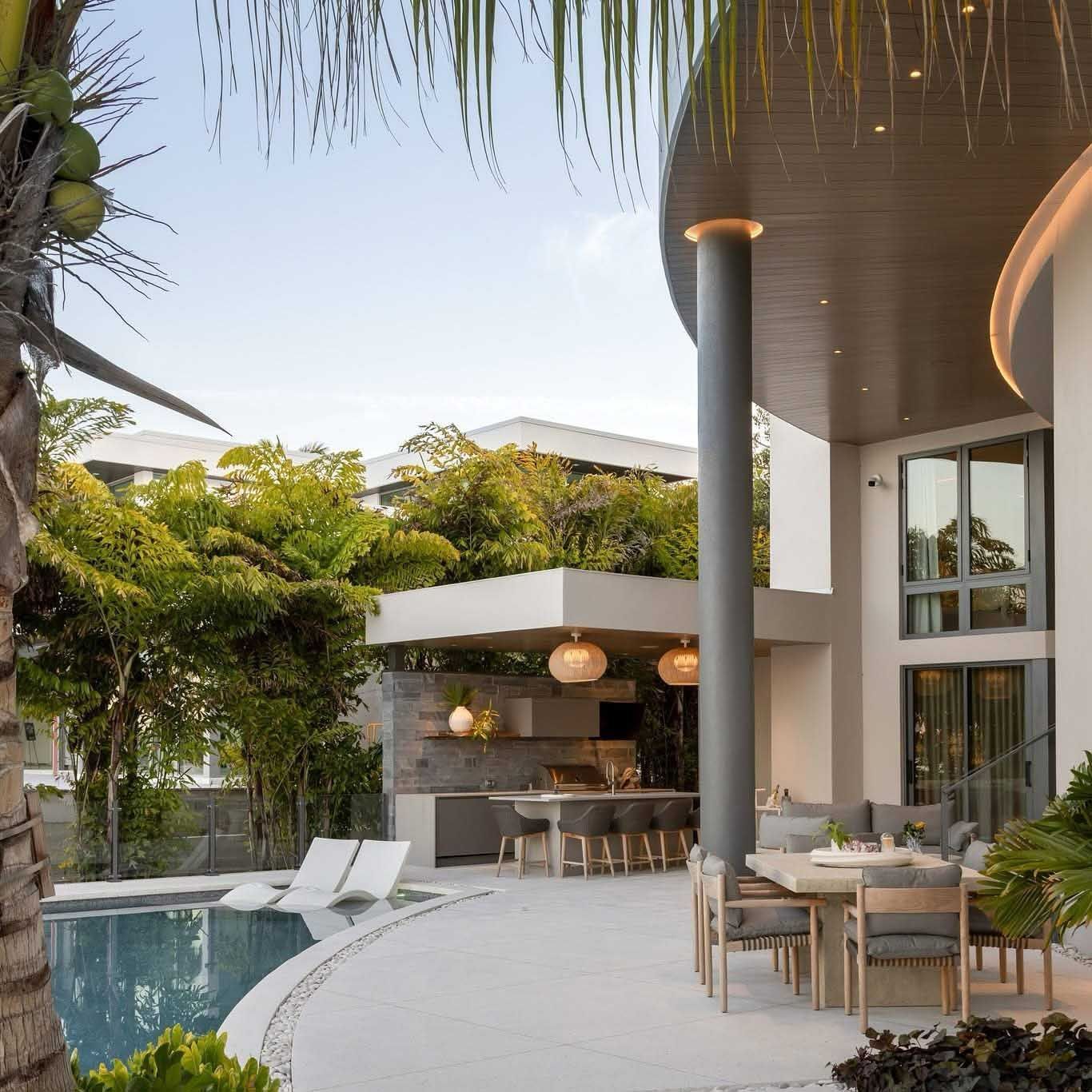 Backyard patio with pool, outdoor kitchen, and dining area. Modern design with white, gray, and green accents.