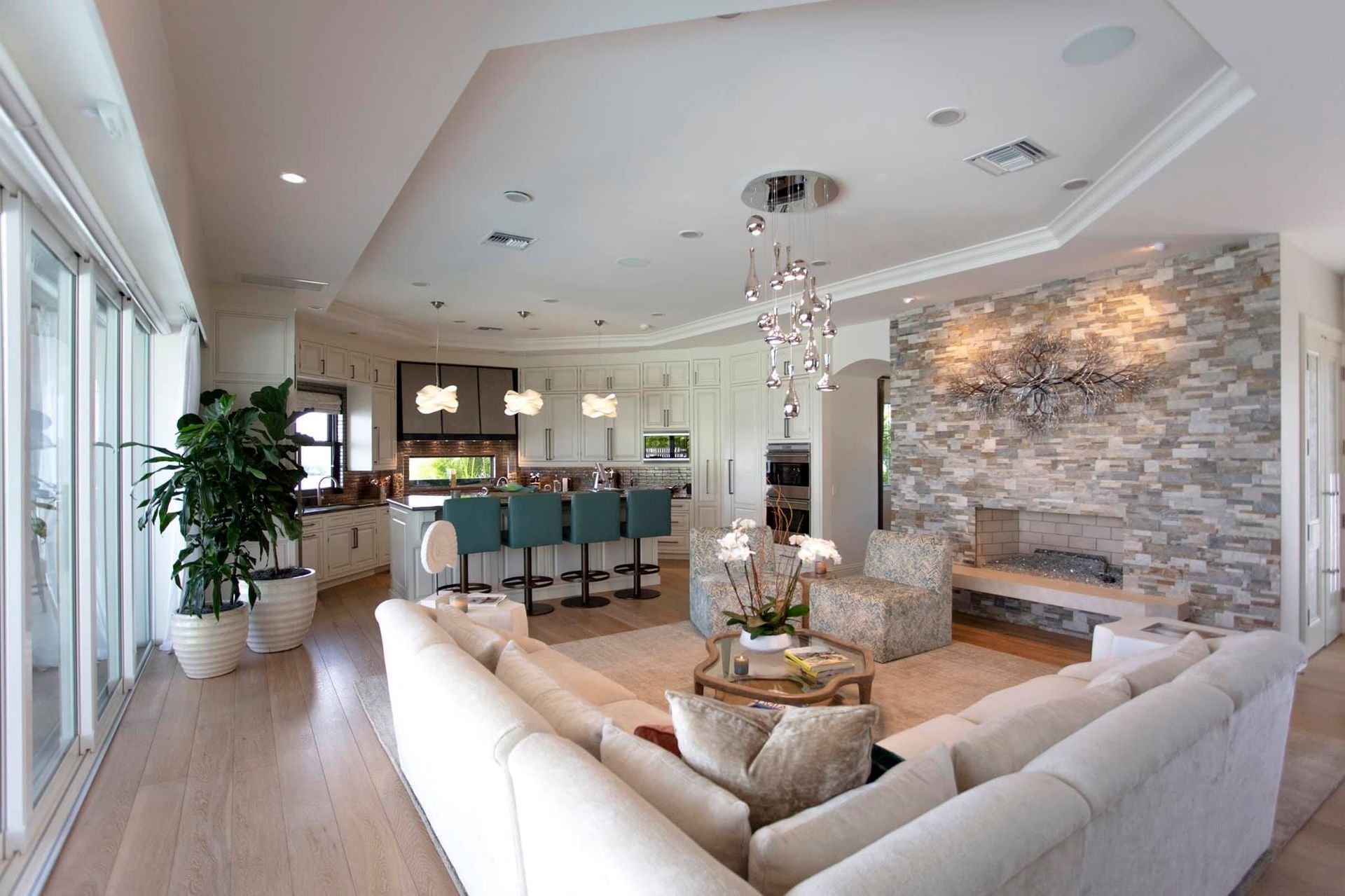 Spacious living area with kitchen, fireplace, and large windows.  Neutral colors, modern decor.