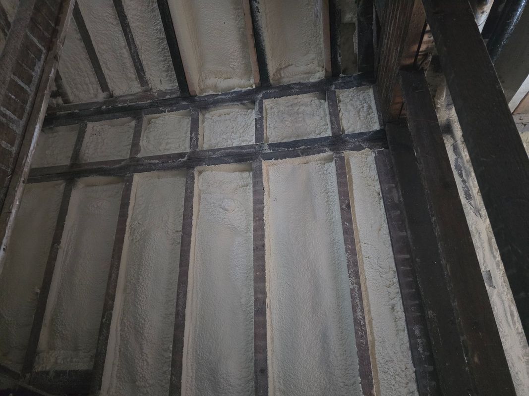 Interior wall with exposed beams and white panels. Dark wooden framing surrounds the panels.