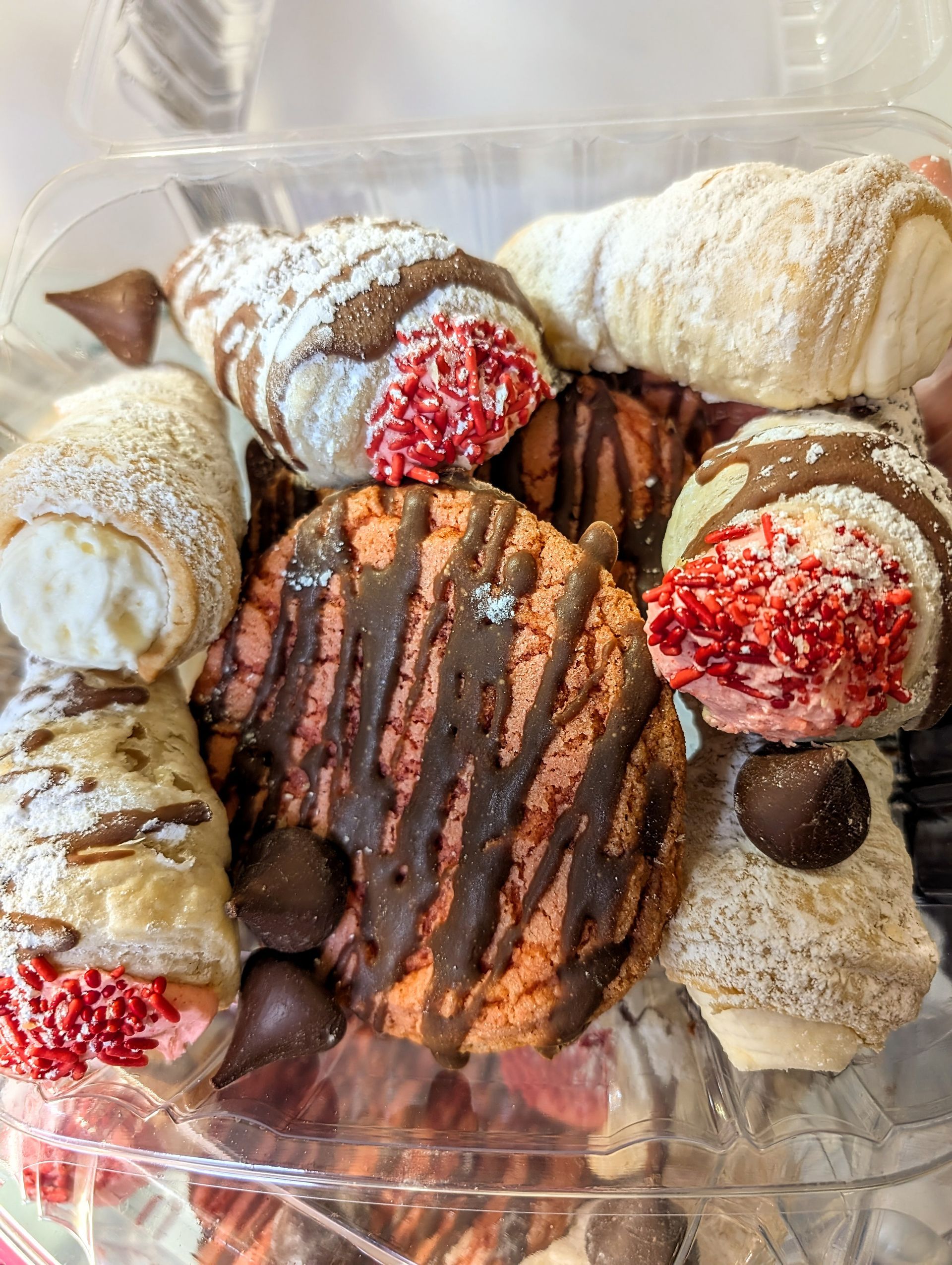 A plastic container filled with a variety of cookies and pastries.