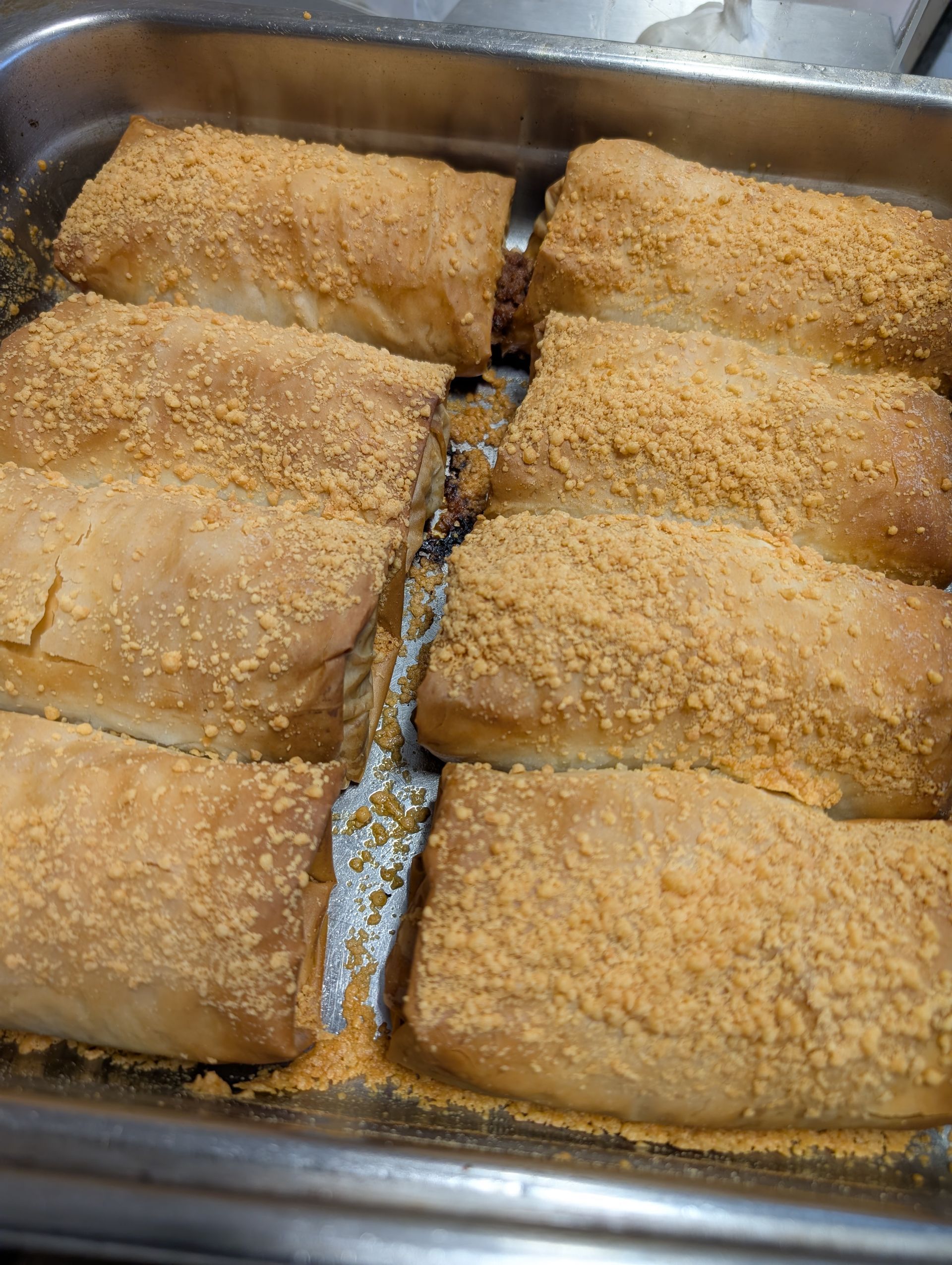 A pan filled with bread rolls covered in crumbs.