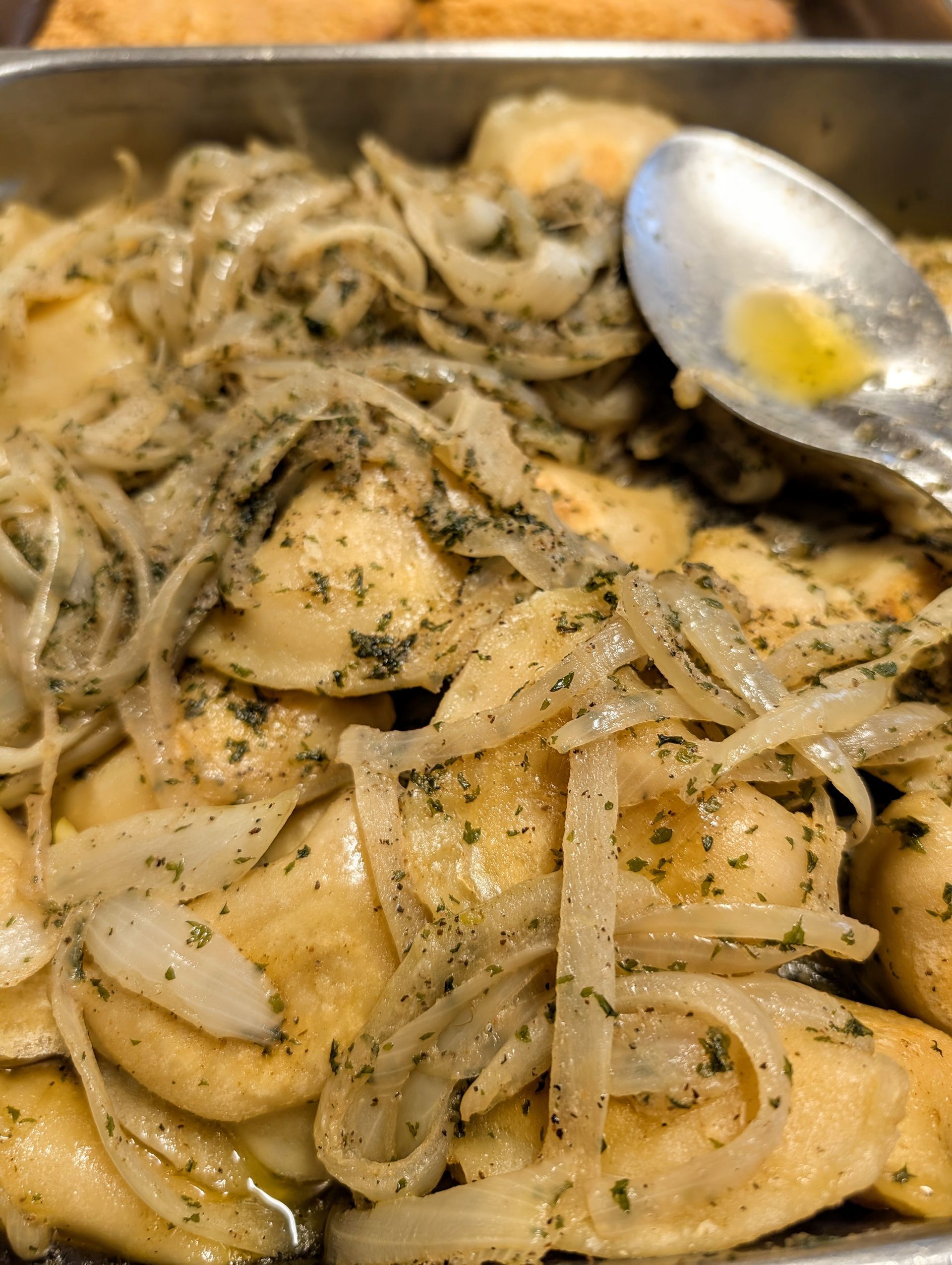A close up of a pan of food with a spoon in it.