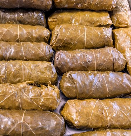 A bunch of stuffed grape leaves are stacked on top of each other on a table.