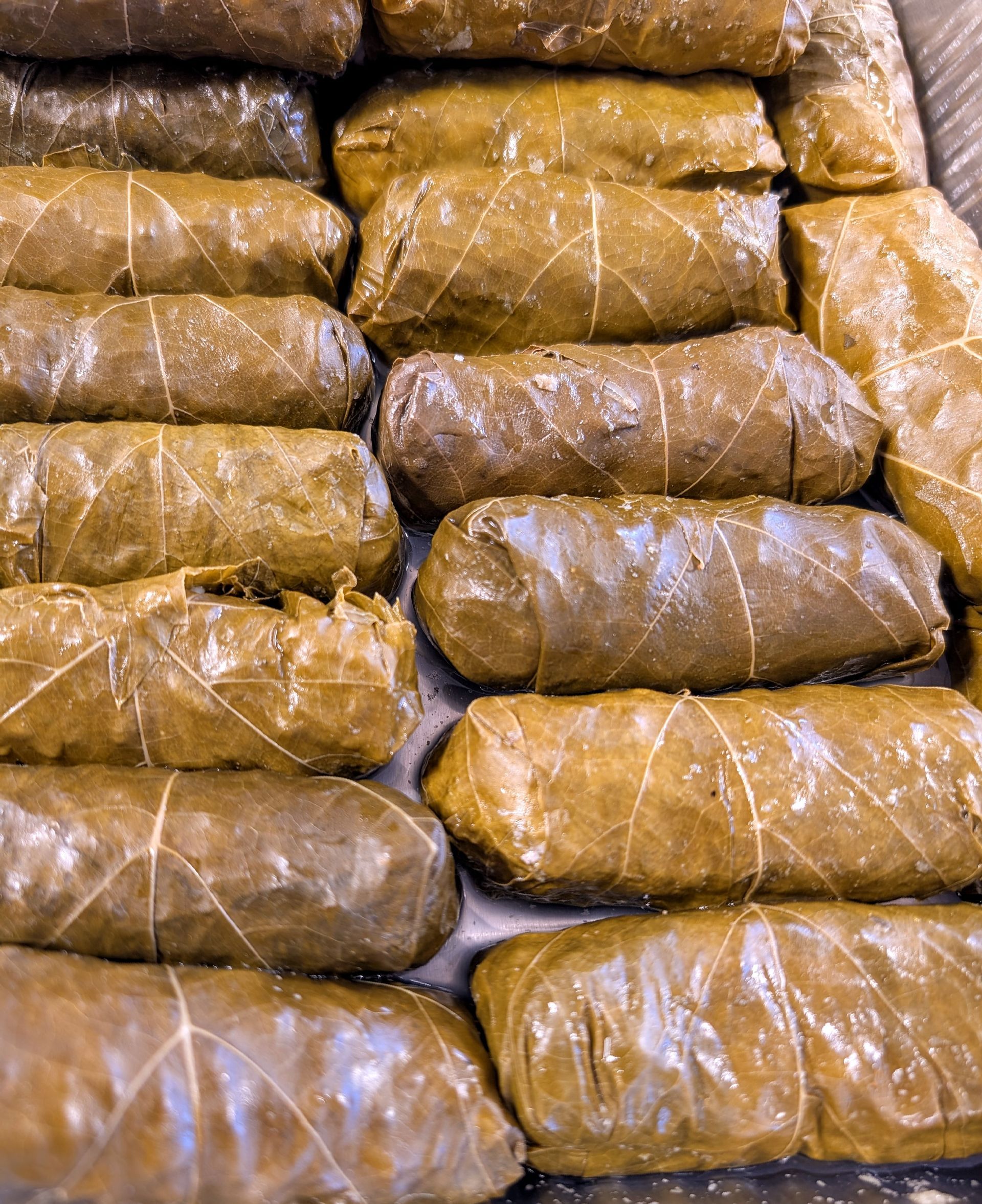 A bunch of stuffed grape leaves are stacked on top of each other on a table.