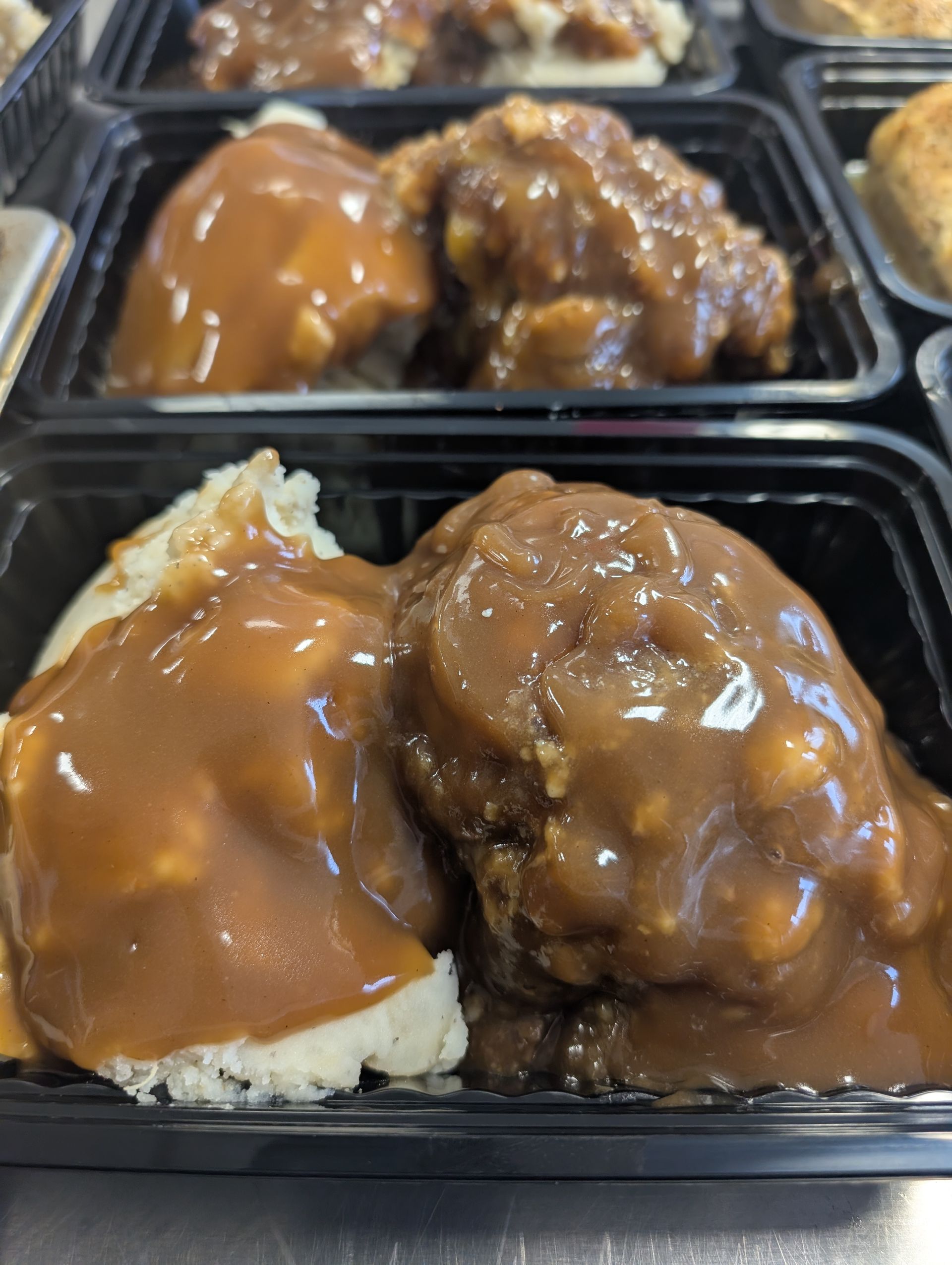 A close up of a tray of food with gravy and mashed potatoes.