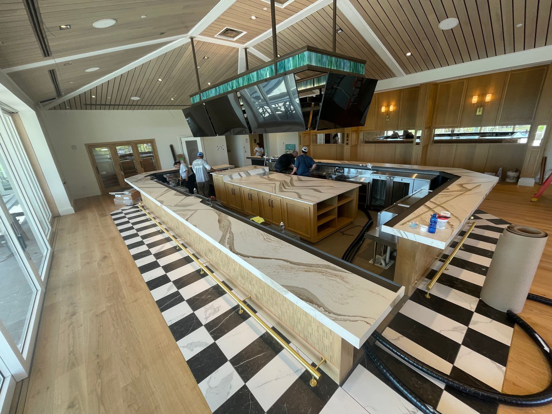Interior view of a bar under construction with checkered floor, wooden accents, and workers.