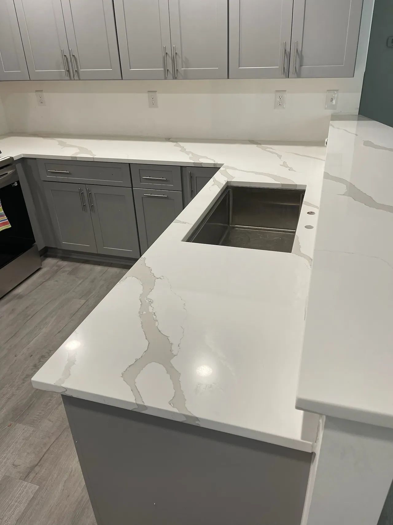 Gray kitchen with white marble countertops and a stainless steel sink.