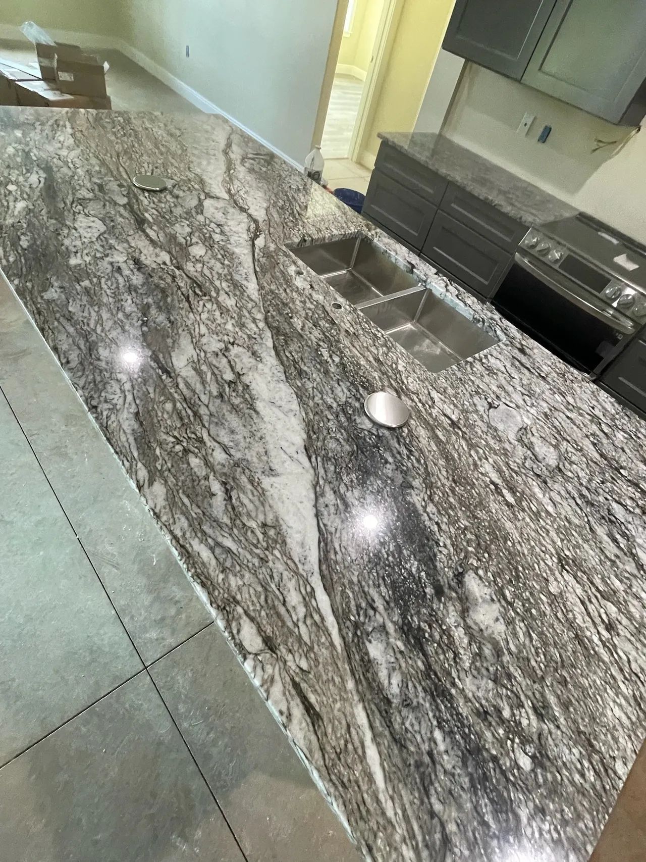 Granite kitchen countertop with two sinks, gray and white swirls, in a modern kitchen.