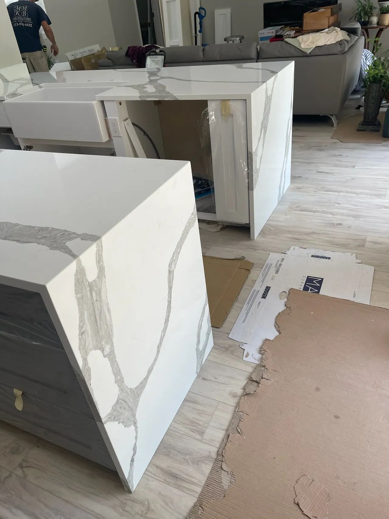 New kitchen island with white quartz countertops and gray veining, being installed in a home.