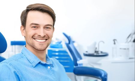 A man is smiling while sitting in a dental chair.