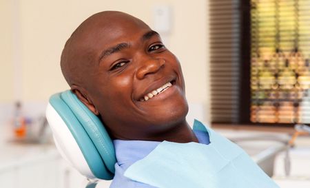 A man is smiling while sitting in a dental chair.