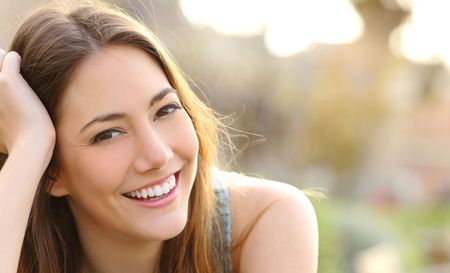 A close up of a woman smiling with her hand in her hair.