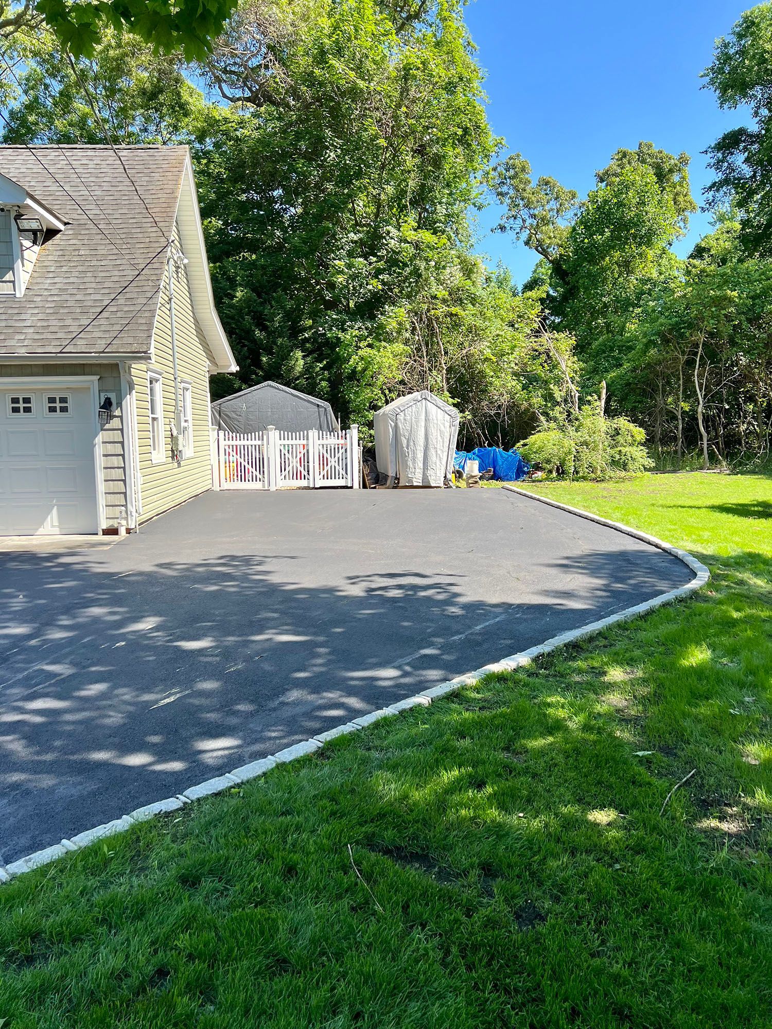 A driveway leading to a house with a garage and a shed.