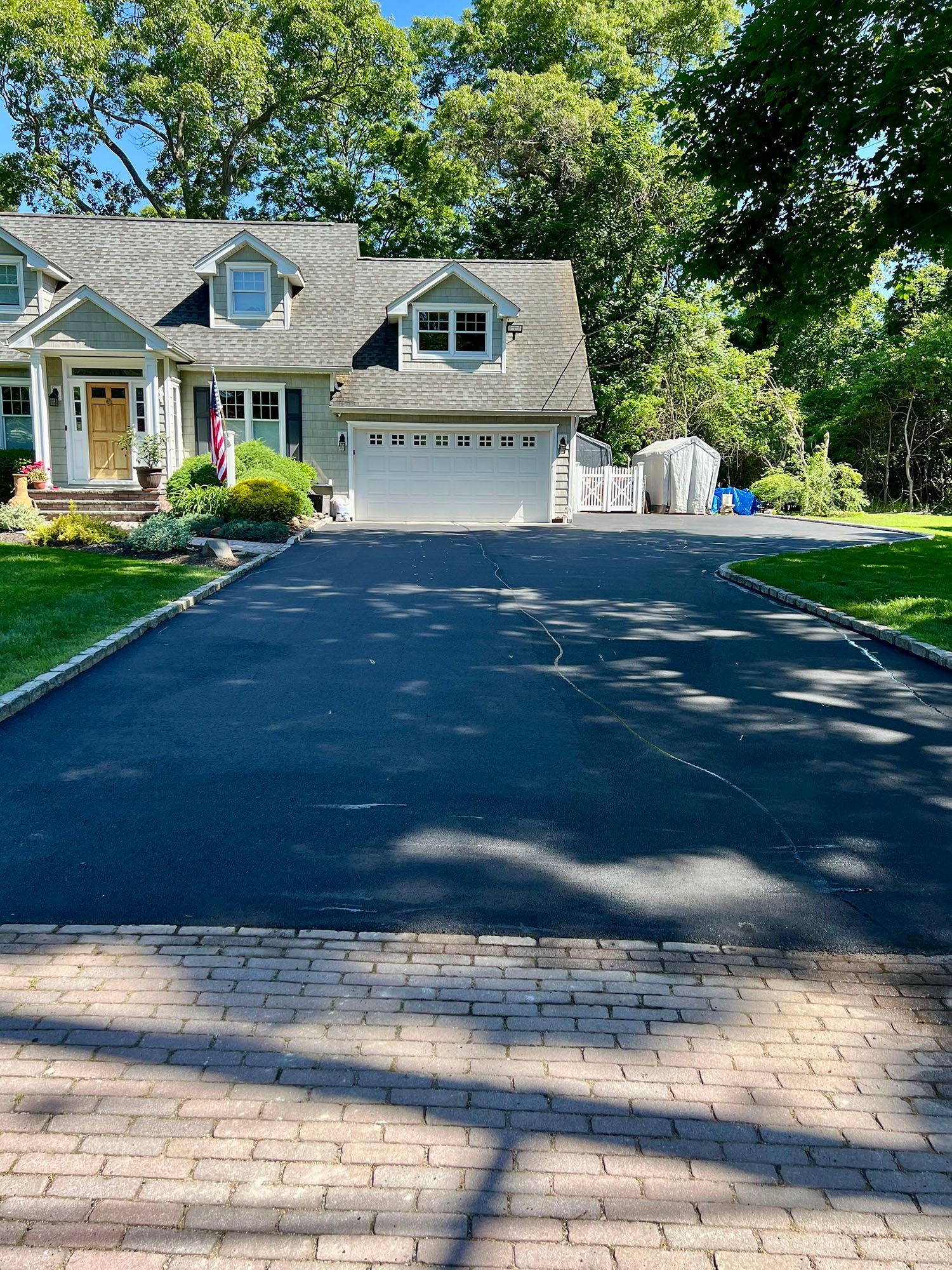 A driveway leading to a house with a garage and a brick driveway.