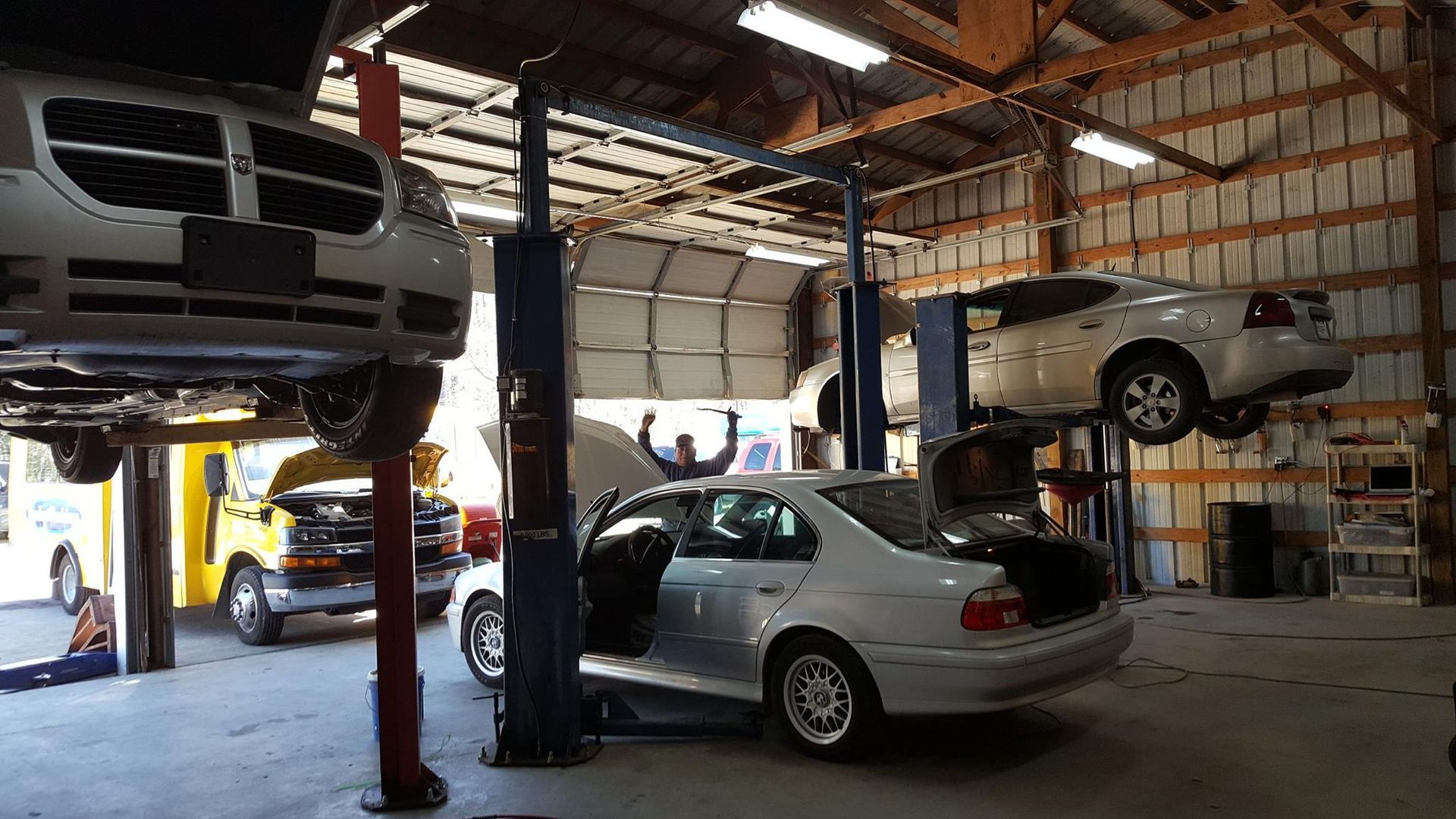 A couple of cars are sitting on a lift in a garage.