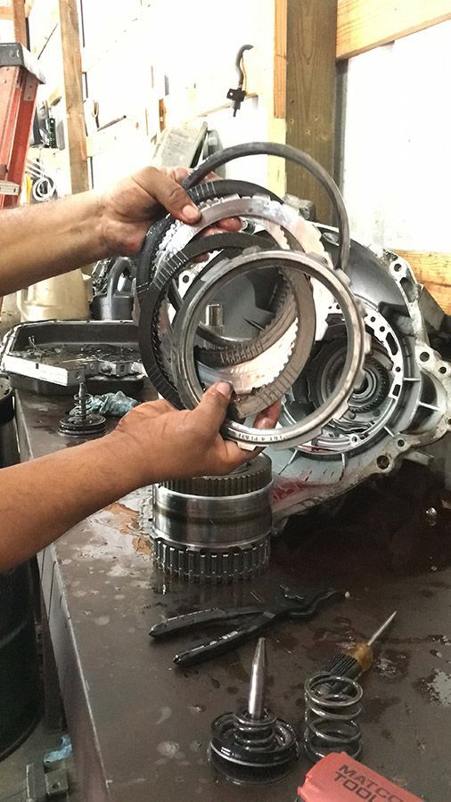 A person is working on a gearbox in a garage.