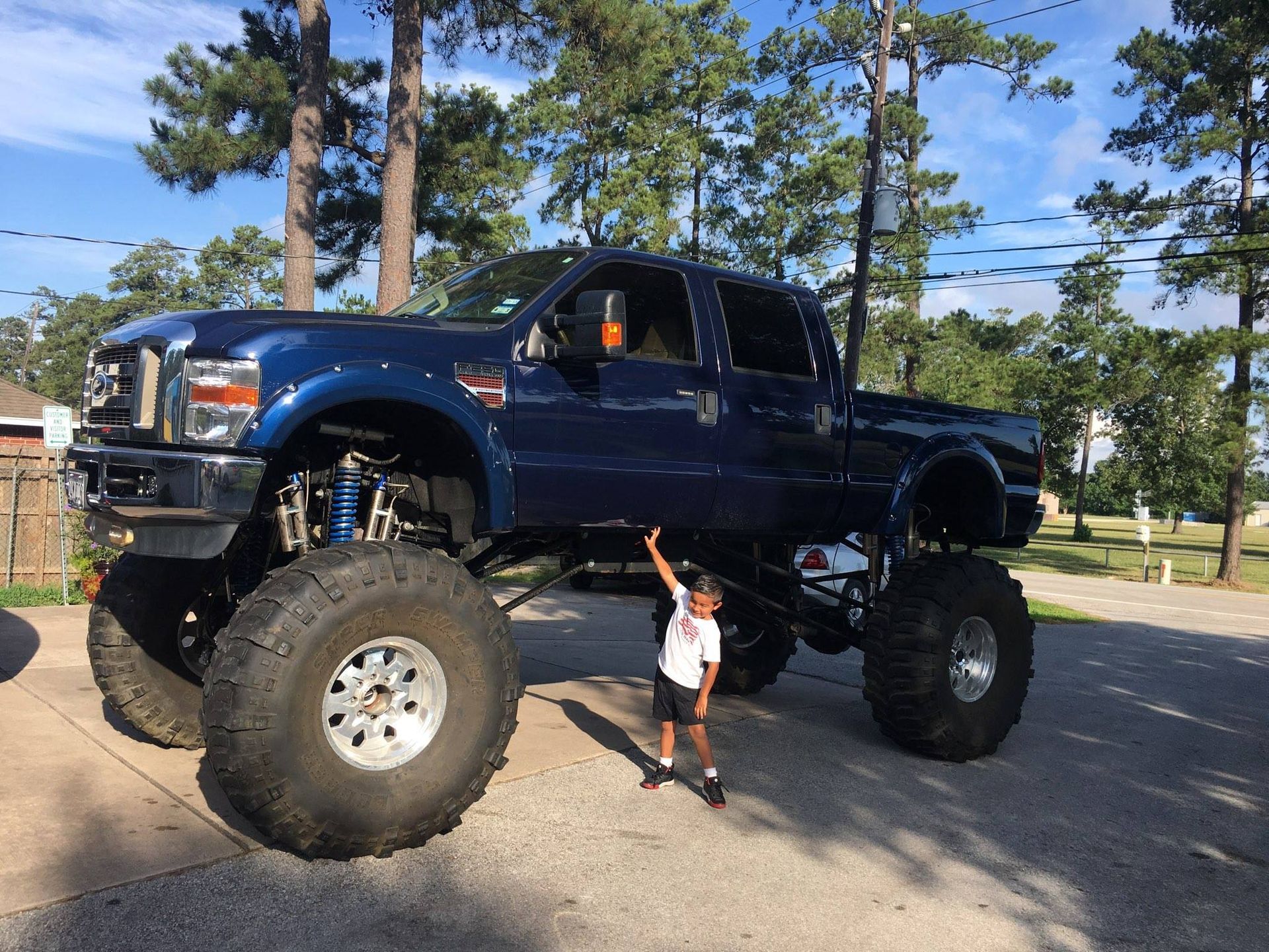 A little boy is standing in front of a very large truck