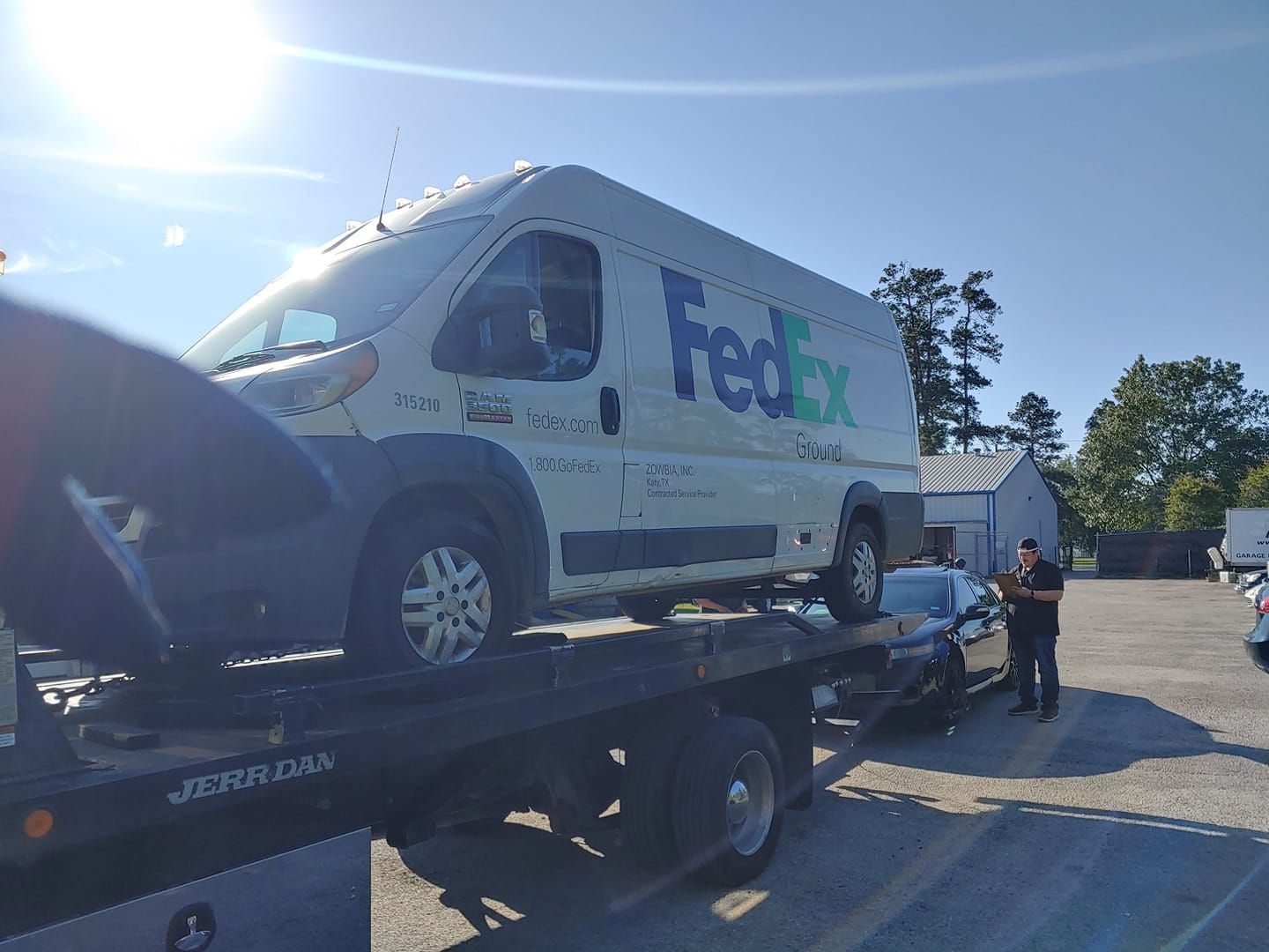 A fedex van is being towed by a tow truck.