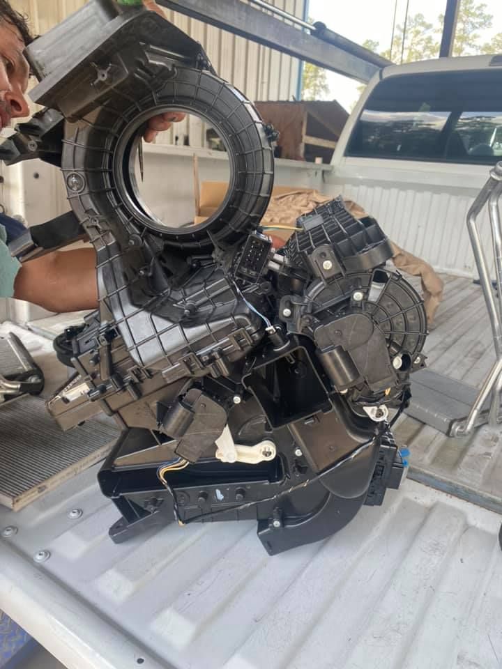 A man is holding a piece of metal on top of a truck bed.