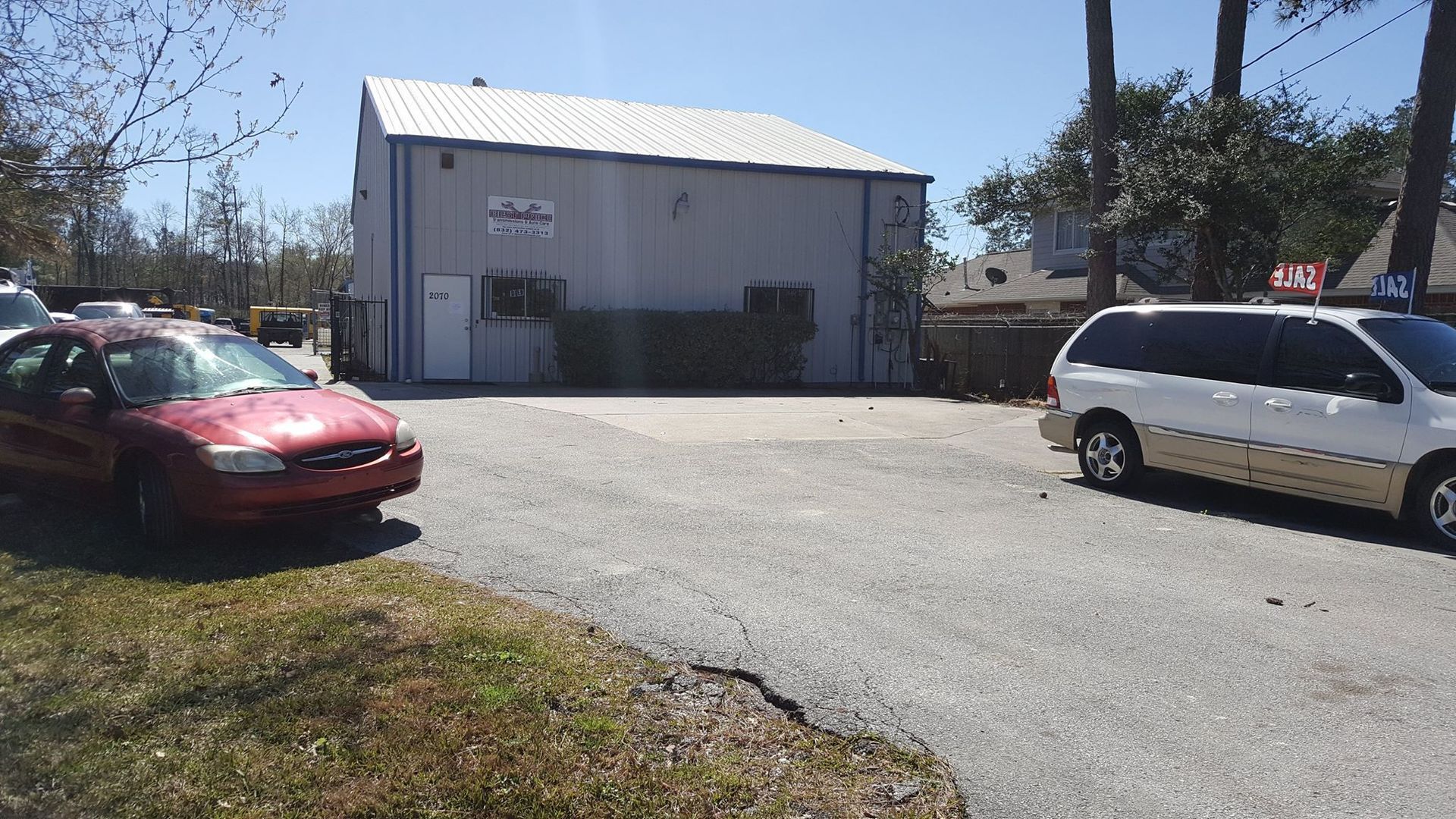 A red car and a white van are parked in front of a building