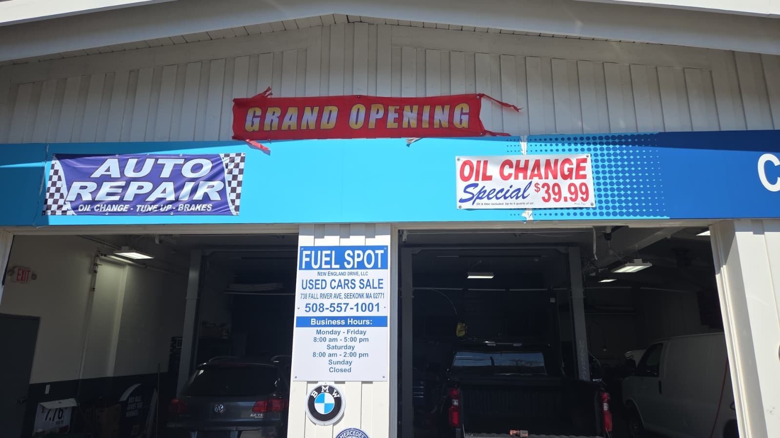 Auto repair shop storefront with blue signs and a red “Grand Opening” banner