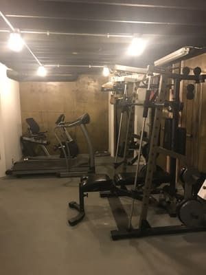 A basement gym filled with lots of exercise equipment.