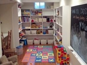 A room with a chalkboard and shelves filled with toys.