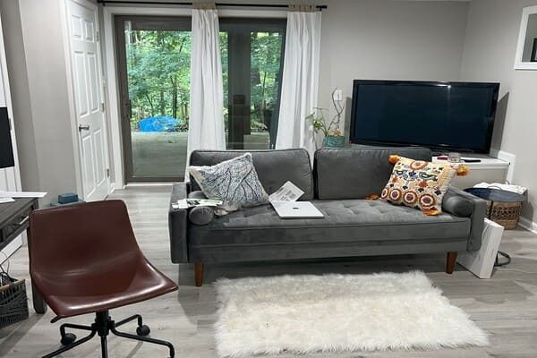 A living room with a couch , chair , television and rug.
