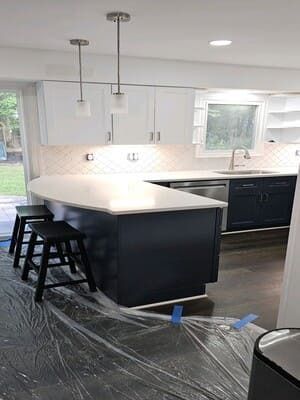A kitchen with blue cabinets and white counter tops is being painted.