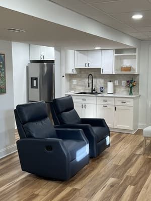 Two black recliner chairs are sitting in a living room next to a kitchen.