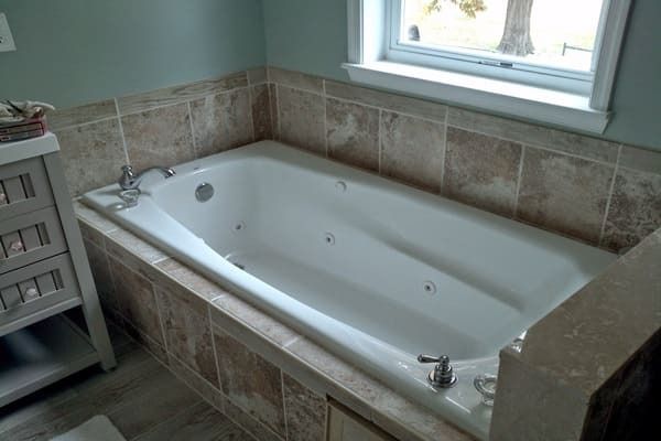 A bathroom with a jacuzzi tub and a window.