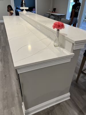 A white counter top with a vase of flowers on it.