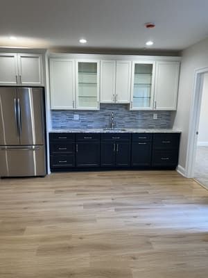 A kitchen with stainless steel appliances, black cabinets, a sink, and a refrigerator.