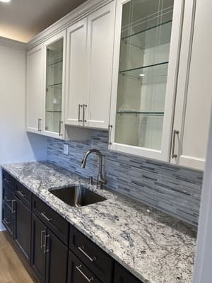 A kitchen with granite countertops, black cabinets, and a sink.