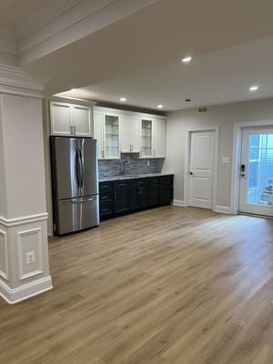 A kitchen with stainless steel appliances, wooden floors, and white cabinets.
