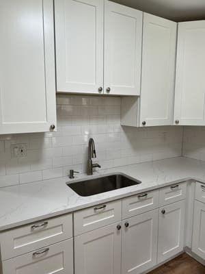 A kitchen with white cabinets and a sink.