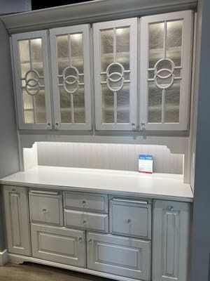 A white cabinet with stained glass doors and drawers in a kitchen.