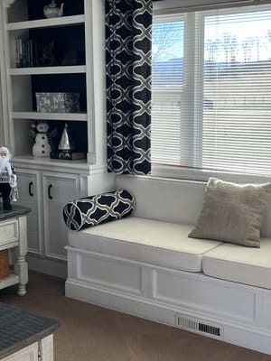A living room with a couch and a window with blinds.