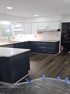 A kitchen with blue cabinets and white counter tops is being remodeled.