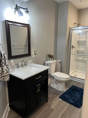A bathroom with a sink , toilet , shower and mirror.