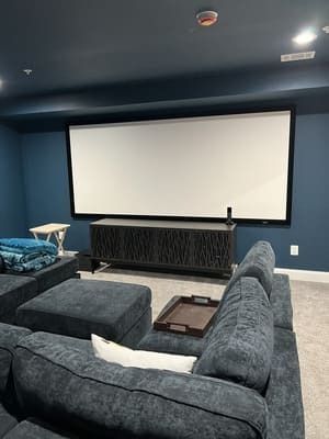 A home theater with a couch , chairs , and a large screen.