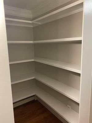 A closet with a lot of shelves and a wooden floor.