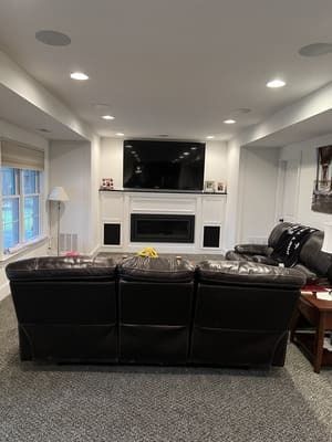 A living room with a couch , chairs , fireplace and television.