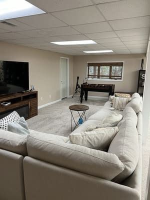 A living room with a couch , table , television and a pool table.